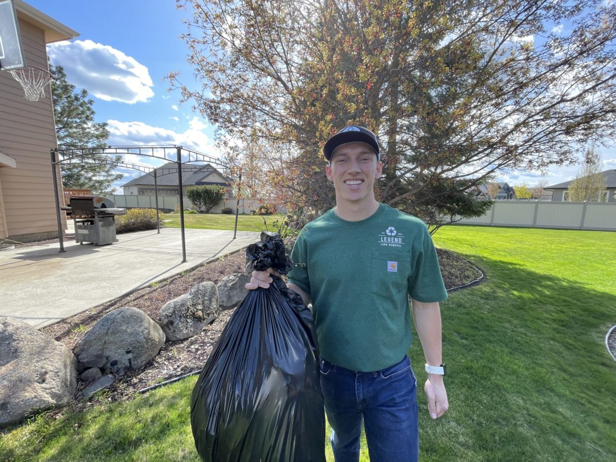 A Legend Junk Removal pro hauling off a bag of yard debris